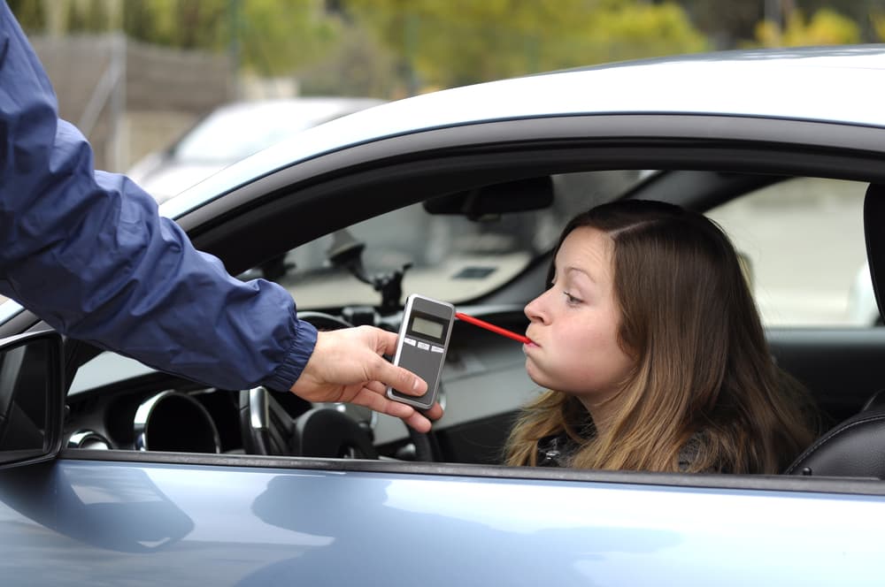 Woman taking a breathalyzer after being pulled over for potential dui