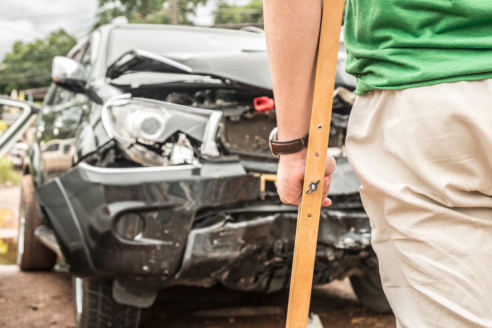 A person injured after a car accident standing with the crutches.