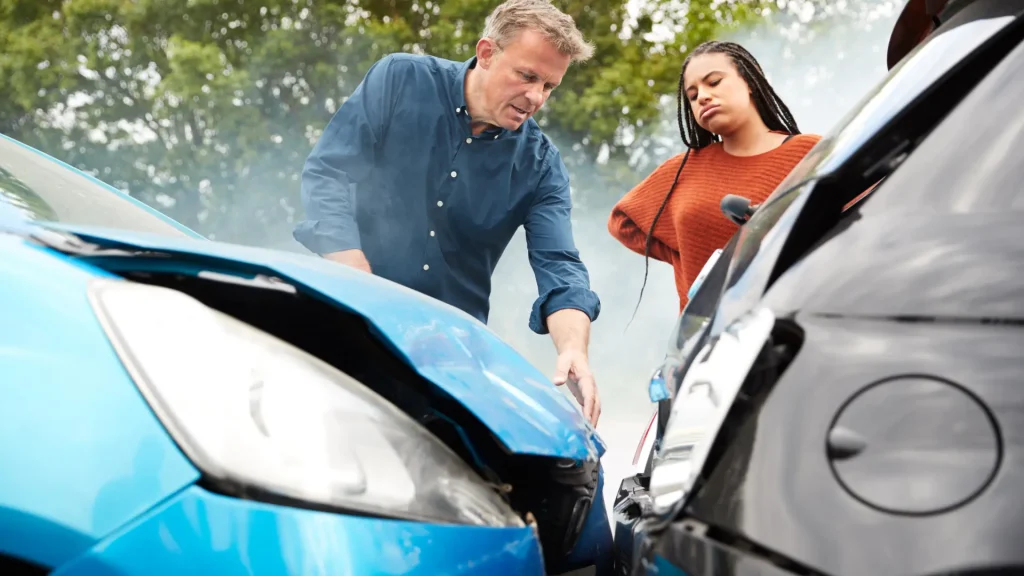 Two people inspecting car damage after an accident